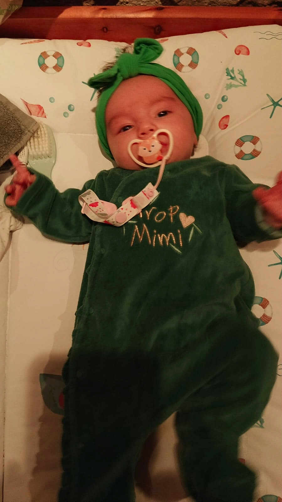 Inès a rejoint le concours — aidez-le/la à gagner de superbes lots ! baby, infant, pacifier, green_clothing, headband, onesie, lying_down, bed, mattress, pattern, soft_lighting, cute, child, indoor, sleepwear, face, person, toddler, comfort, young_child