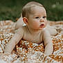 baby, infant, child, blanket, outdoor, nature, curious, face, head, skin, expression, pattern, orange, white, lying_down, closeup, portrait, young, soft_light, background_blur