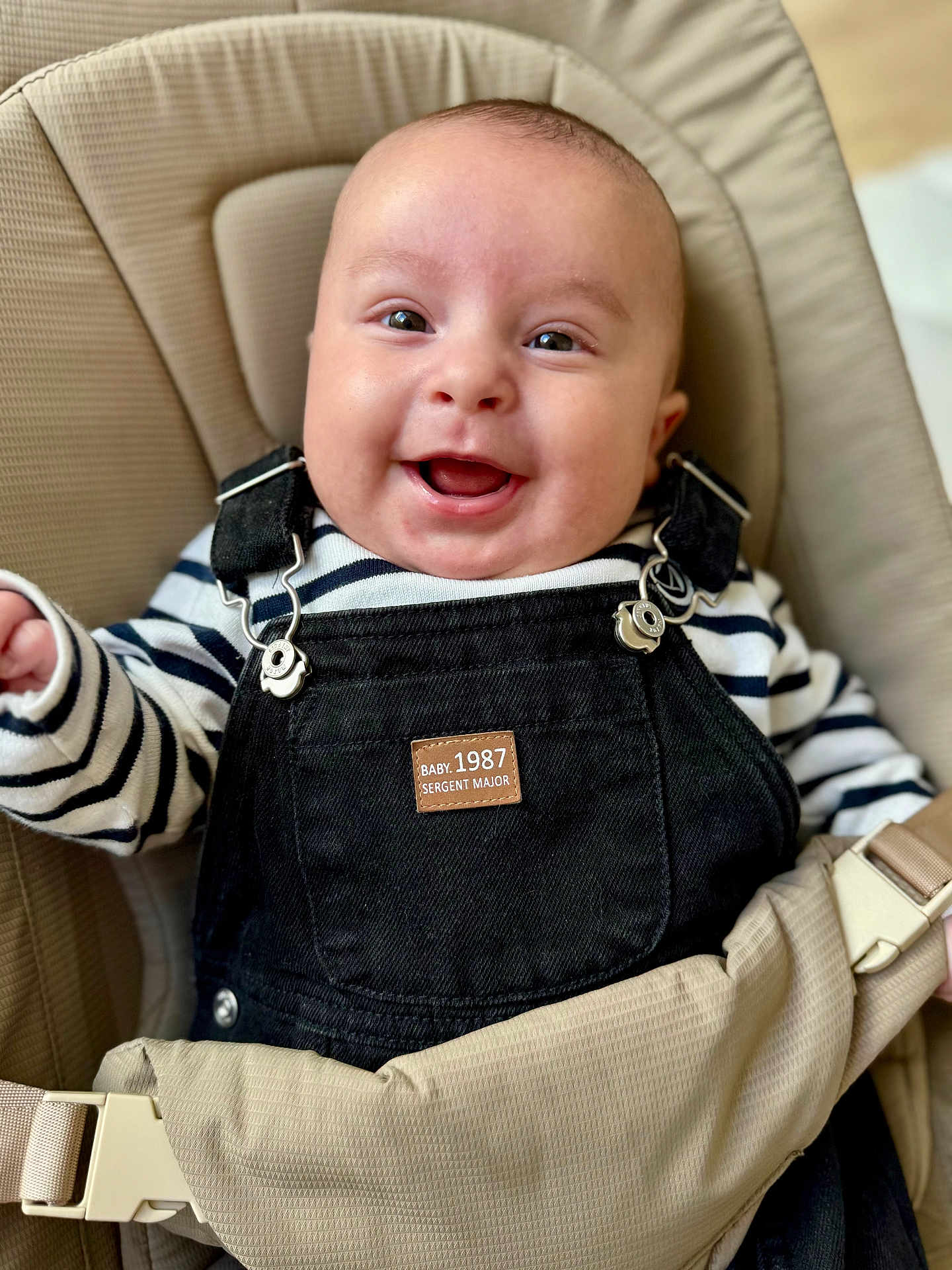 Arthur participe au concours pour gagner de l'argent avec cette photo : baby, smiling, infant, overalls, striped_shirt, baby_carrier, seat, happy, face, child, clothing, person, cute, indoor, portrait, young_child, sitting, closeup, baby_fashion, expression