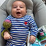 Arthur participe au concours pour gagner de l'argent avec cette photo : baby, infant, striped_clothing, blue_and_white, heart_patch, toy, fabric_book, cushion, smiling, happy, indoor, child, cute, playful, lying_down, hand, face, head, soft_toys, colorful