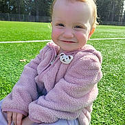 Alice joined the competition — help win amazing prizes! toddler, child, smile, pink_jacket, fluffy_clothing, bear_charm, sitting, artificial_turf, grass, outdoor, sunlight, trees, portrait, close_up, happy, hands, face, wispy_hair, playground, weekend