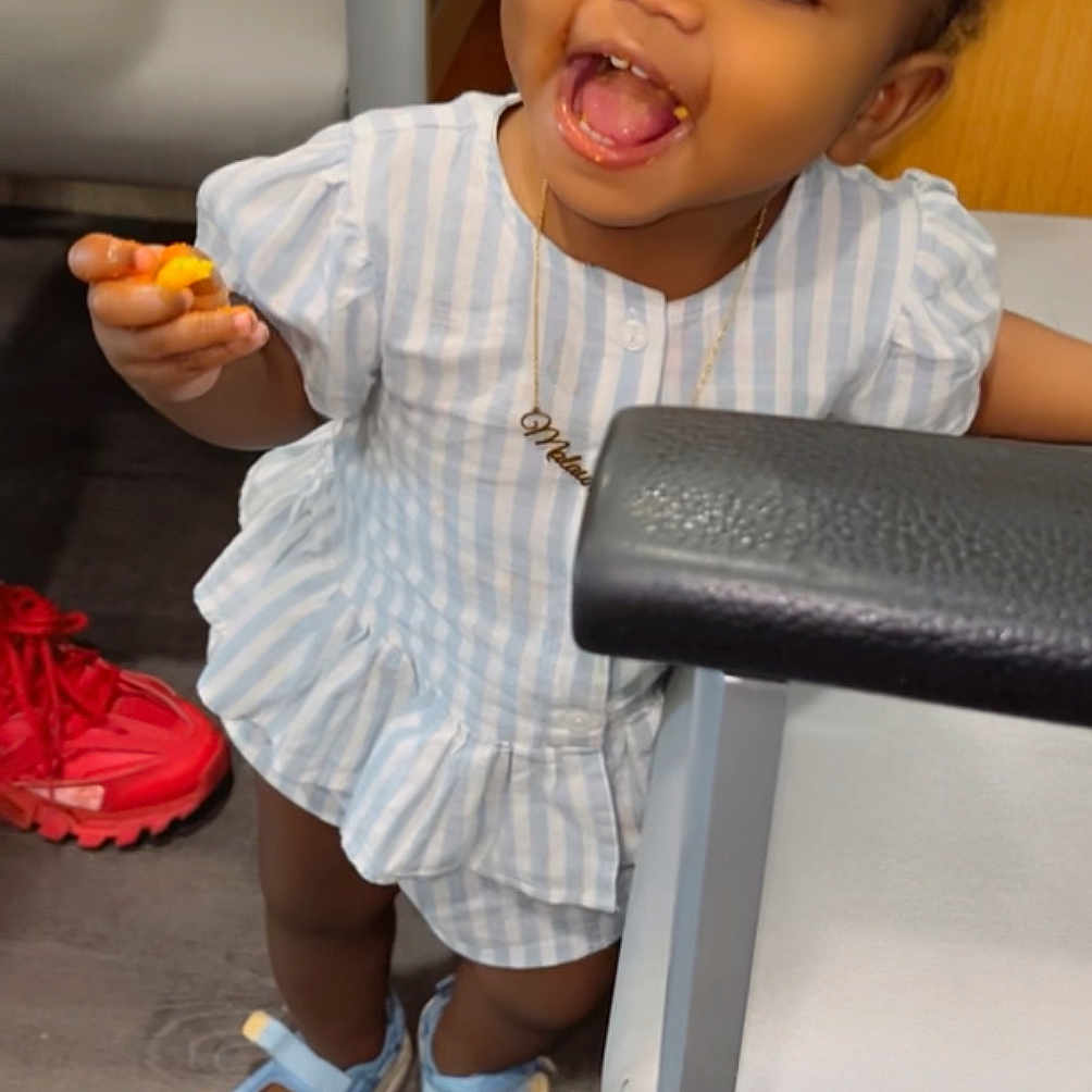 Malaun joined the competition — help win amazing prizes! chair, child, cute, dress, floor, footwear, furniture, hair_bows, happy, indoor, person, playful, portrait, red_shoes, sandals, smiling, snack, toddler, wooden_floor, young_child