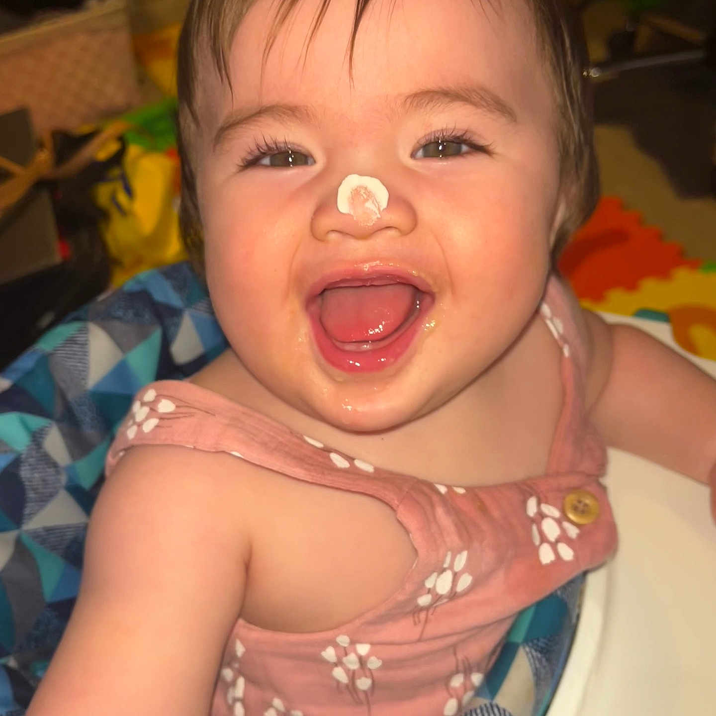 Nicholette is registered to the contest to win money with this photo: baby, child, closeup, cream, cute, expression, face, fun, happy, high_chair, indoor, infant, joyful, nose, person, pink_clothing, playful, sitting, smile, young_child