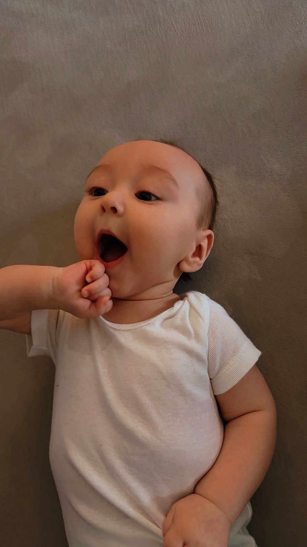 Noah joined the competition — help win amazing prizes! baby, infant, child, onesie, white_clothing, lying_down, fist, mouth_open, expression, skin, head, arm, hand, cute, adorable, soft_surface, portrait, young, person, indoors