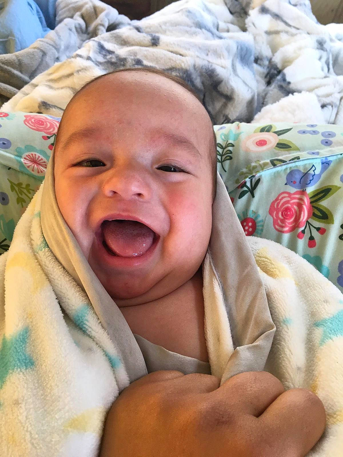 Vincent is registered to the contest to win money with this photo: baby, baby_laughing, bedding, child, comfort, eye, facial_expression, gesture, happy, head, human, linens, mouth, person, skin, smile, textile, thumb, toddler, tooth
