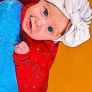 Méline a rejoint le concours — aidez-le/la à gagner de superbes lots ! baby, blue_cushion, bright_colors, child, cute, expression, face, happy, hat, headwear, indoors, infant, person, playful, portrait, red_clothing, smiling, toddler, yellow_background, young
