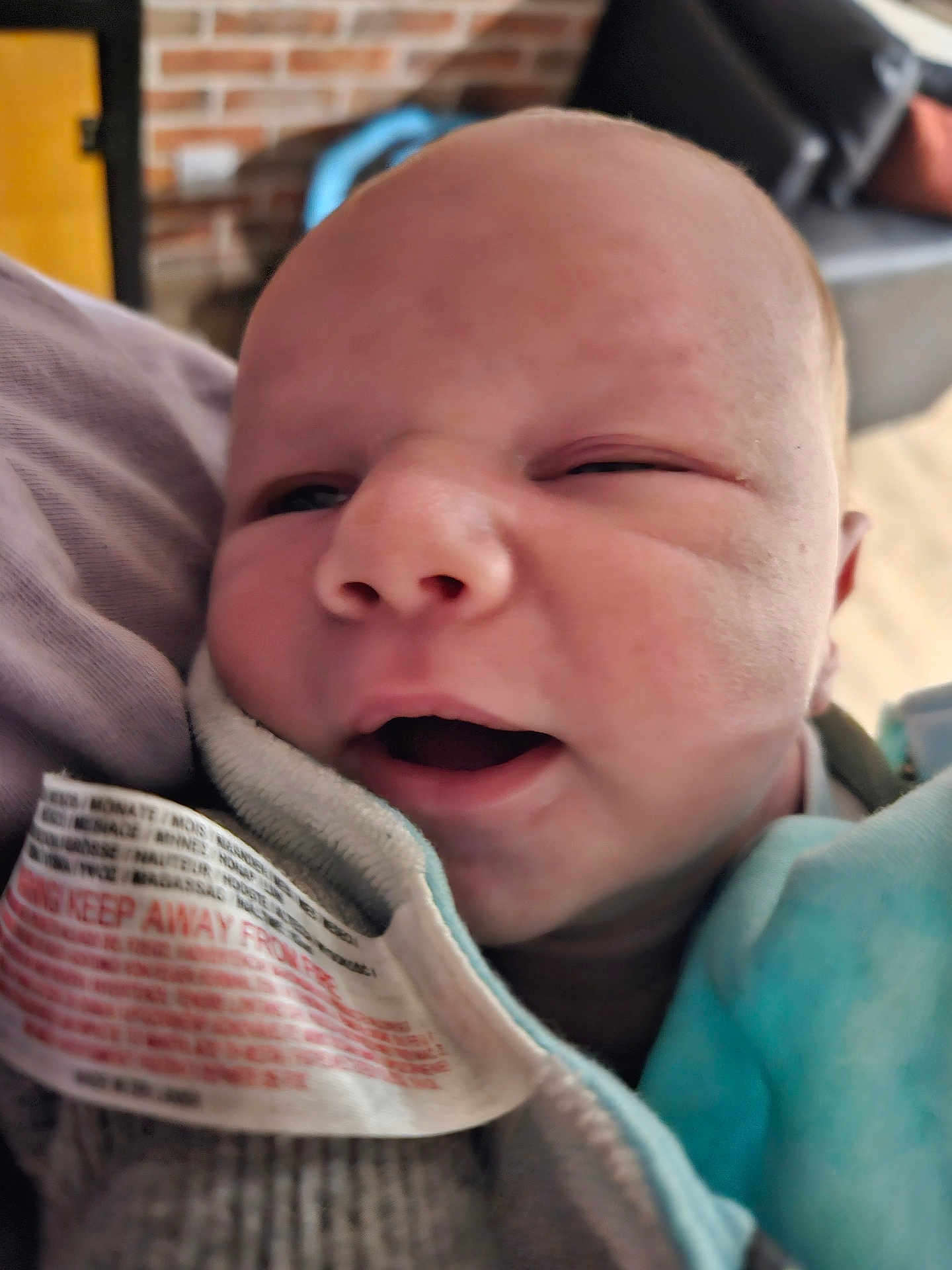 Malo a rejoint le concours — aidez-le/la à gagner de superbes lots ! baby, newborn, close_up, face, infant, mouth_open, eyes_partly_closed, clothing, fabric, tag, indoor, blurred_background, cozy, soft_texture, person, skin, head, portrait, sleepy, young_child