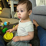 Liam joined the competition — help win amazing prizes! toddler, child, toy, indoor, carpet, stacking_cups, curious, sitting, casual_clothing, living_room, sofa, footwear, person, playtime, colorful, home, furniture, soft_lighting, expression, floor