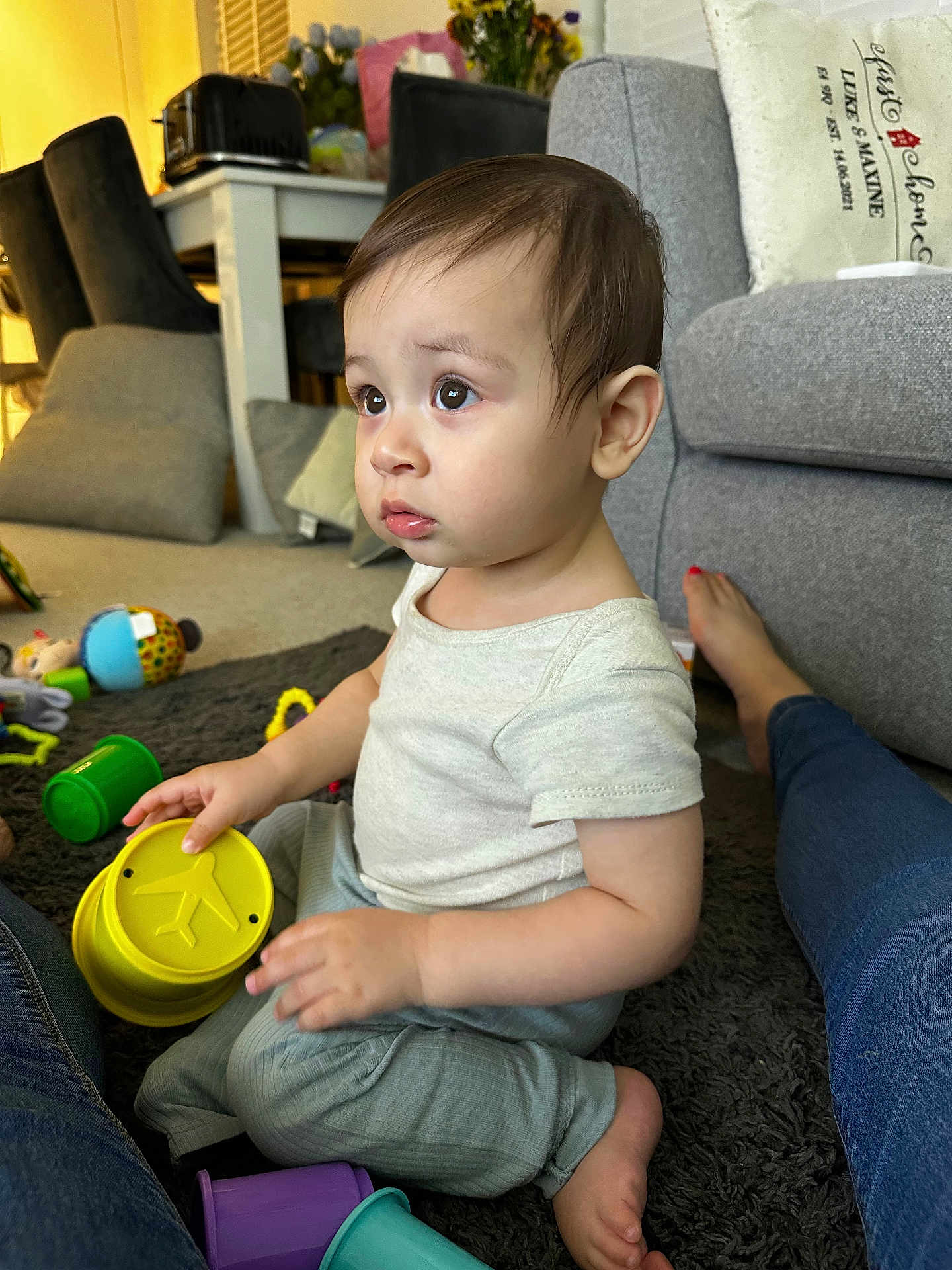 Liam joined the competition — help win amazing prizes! toddler, child, toy, indoor, carpet, stacking_cups, curious, sitting, casual_clothing, living_room, sofa, footwear, person, playtime, colorful, home, furniture, soft_lighting, expression, floor