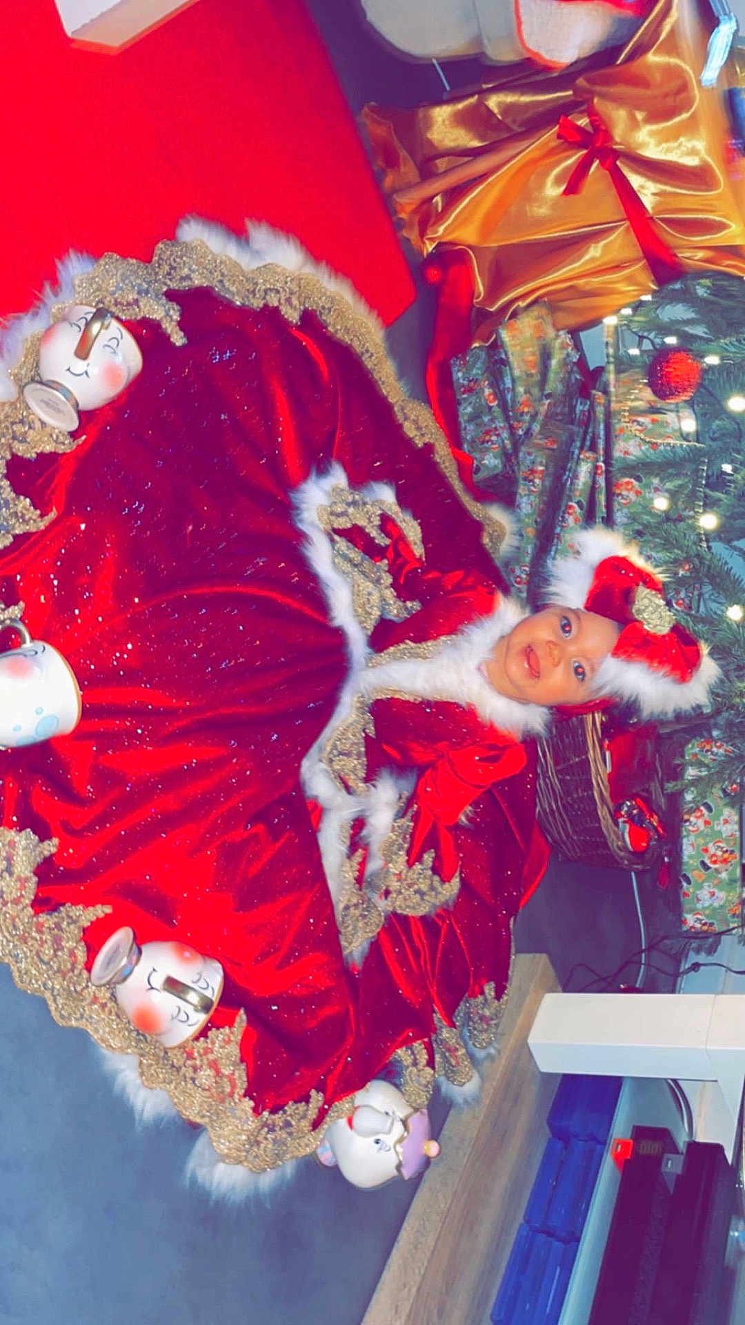 Djeyslie participe au concours pour gagner de l'argent avec cette photo : baby, child, christmas, holiday, red_dress, festive, gift_boxes, christmas_tree, decorations, smiling, indoor, floor, hat, fur_trim, celebration, holiday_outfit, cute, festive_attire, seasonal, joyful