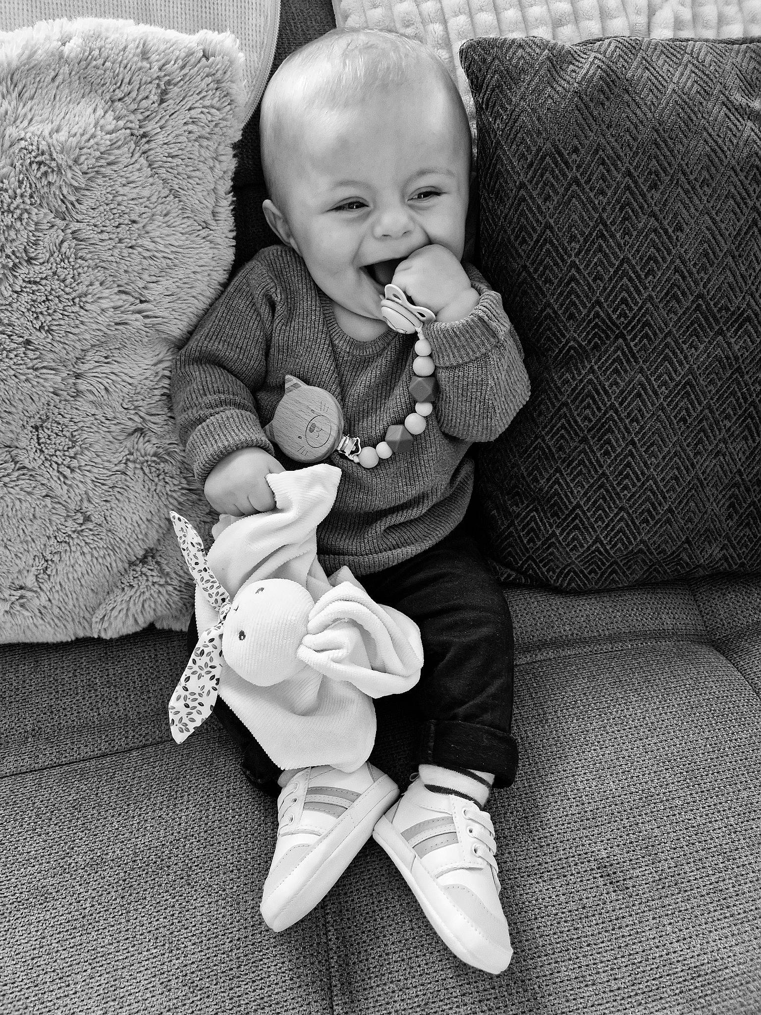 Léo a rejoint le concours — aidez-le/la à gagner de superbes lots ! arm, baby, baby_toddler_clothing, child, comfort, couch, eye, face, finger, furniture, hand, happy, head, human_body, lap, leg, person, skin, smile, sock