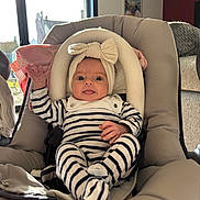 élise a rejoint le concours — aidez-le/la à gagner de superbes lots ! baby, infant, car_seat, striped_clothing, headband, bow, smile, hand, indoors, window, sunlight, cozy, cute, child, person, seat, fabric, soft, comfort, playful