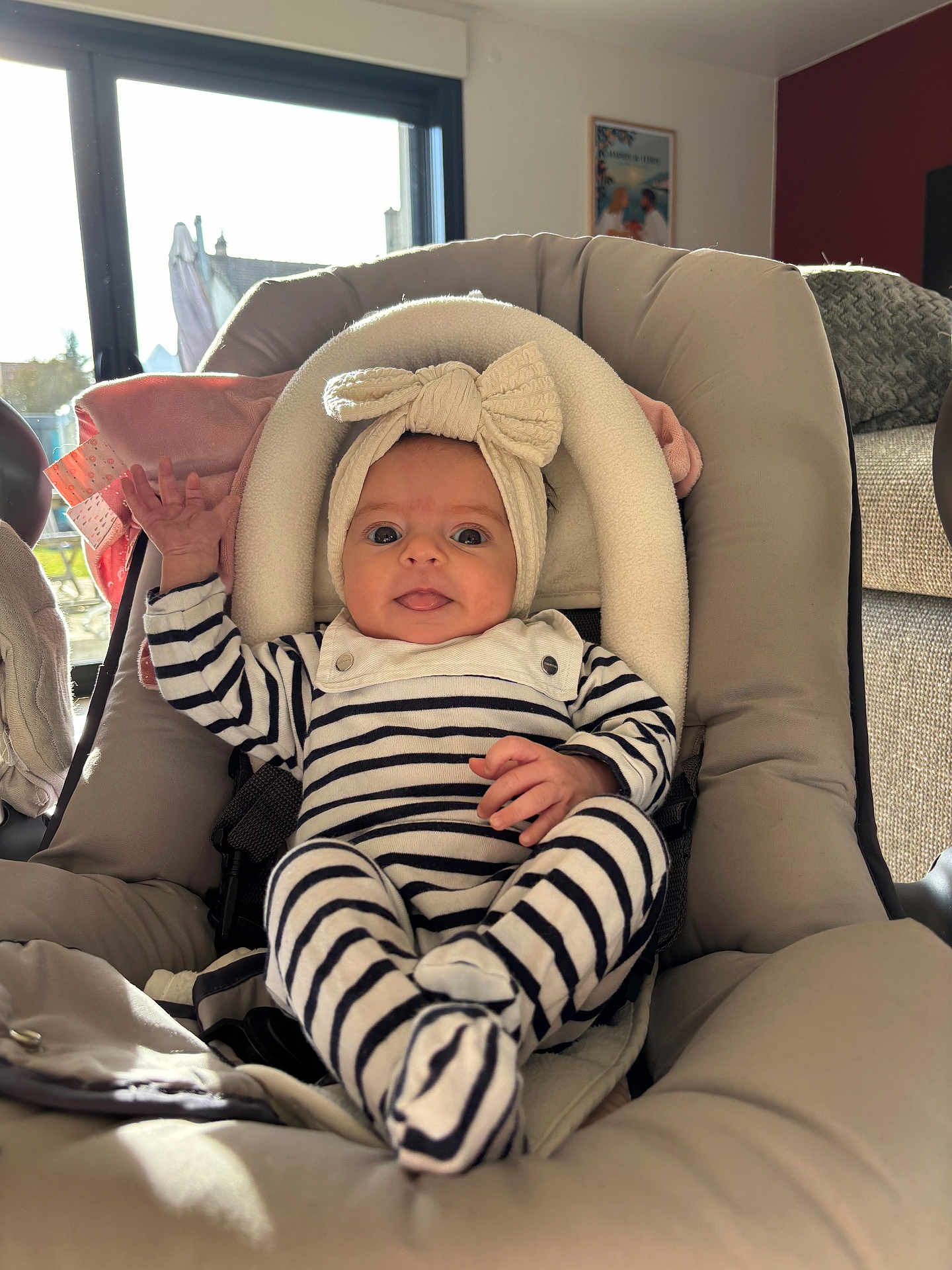 élise a rejoint le concours — aidez-le/la à gagner de superbes lots ! baby, infant, car_seat, striped_clothing, headband, bow, smile, hand, indoors, window, sunlight, cozy, cute, child, person, seat, fabric, soft, comfort, playful