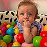Everly is registered to the contest to win money with this photo: baby, ball_pit, blue_eyes, child, clothing, colorful, curly_hair, cute, face, fingers, green, hand, indoor, pink, plastic_balls, play_area, portrait, sitting, toddler, yellow