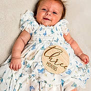 Everly joined the competition — help win amazing prizes! baby, infant, child, smiling, dress, butterfly_pattern, hair_bow, wooden_sign, milestone, lying_down, cute, soft_background, portrait, skin, hand, face, happy, young_child, white_dress, three_months
