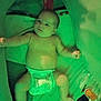 baby, diaper, infant, lying_down, arm_outstretched, enclosed_space, green_tint, soft_lighting, baby_items, cozy, child, person, cute, indoor, blanket, toy, face, head, skin, newborn