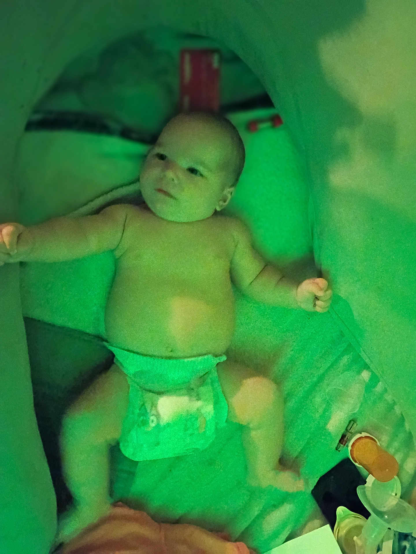 Matthew is registered to the contest to win money with this photo: baby, diaper, infant, lying_down, arm_outstretched, enclosed_space, green_tint, soft_lighting, baby_items, cozy, child, person, cute, indoor, blanket, toy, face, head, skin, newborn