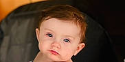 Ryleigh is registered to the contest to win money with this photo: baby, child, infant, person, face, hand, striped_clothing, colorful, sitting, indoor, portrait, blue_eyes, curly_hair, young_child, table, blurry_background, string_lights, soft_lighting, expression, closeup