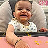Navisha joined the competition — help win amazing prizes! baby, high_chair, messy, food, orange_food, smiling, happy, kitchen, indoor, child, face, hand, bib, table, playful, cute, person, infant, mess, feeding
