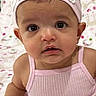 baby, child, girl, pink_dress, headband, floral, portrait, indoors, cute, infant, face, eyes, expression, sitting, soft_background, person, adorable, young_child, clothing, closeup