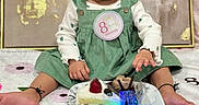 Navisha joined the competition — help win amazing prizes! baby, infant, child, girl, green_dress, headband, bow, cake, strawberry, chocolate, plate, blanket, flower_pattern, celebration, birthday, milestone, sitting, cute, indoors, portrait