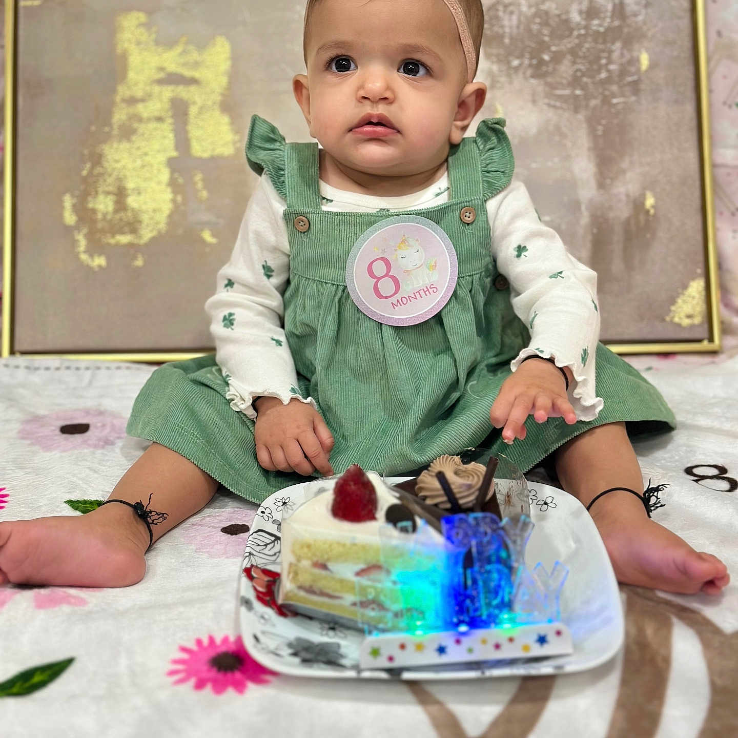 Navisha joined the competition — help win amazing prizes! baby, infant, child, girl, green_dress, headband, bow, cake, strawberry, chocolate, plate, blanket, flower_pattern, celebration, birthday, milestone, sitting, cute, indoors, portrait