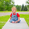 Beau is registered to the contest to win money with this photo: baby, child, toddler, portrait, outdoor, garden, grass, trees, concrete, platform, overalls, striped_clothing, red_shirt, sitting, barefoot, blonde_hair, facial_expression, nature, daylight, photography