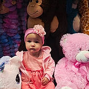 Medeina is registered to the contest to win money with this photo: baby, child, pink_dress, headband, flower, plush_toy, unicorn, monkey, teddy_bear, stuffed_animal, sitting, indoors, cute, portrait, soft_toys, childrens_toy, toy_collection, child_fashion, serious_expression, colorful