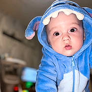 Ezio participe au concours pour gagner de l'argent avec cette photo : baby, blue_onesie, child, closeup, costume, cute, expression, eyes, face, hood, indoor, infant, looking_at_camera, mouth_open, onesie, person, plush, portrait, soft, young_child