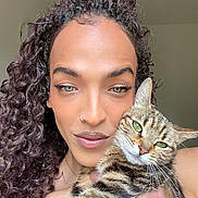 Clochette participe au concours pour gagner de l'argent avec cette photo : background, calm, cat, close_up, curly_hair, expression, face, feline, green_eyes, holding, indoor, makeup, natural_light, nose_ring, person, pet, portrait, skin, striped_cat, tabby_cat