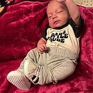 Kaylum is registered to the contest to win money with this photo: adorable, baby, black_and_white_shoes, blanket, casual, child, clothing, cute, gray_pants, home, indoor, infant, newborn, person, red, relaxed, resting, sleeping, sneakers, soft