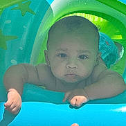 Adonai joined the competition — help win amazing prizes! baby, infant, pool_float, water_toy, child, outdoor, summer, inflatable, blue, green, skin, face, arms, hand, thumb, expression, serious, water_drops, sunlight, playtime