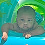 baby, infant, pool_float, water_toy, child, outdoor, summer, inflatable, blue, green, skin, face, arms, hand, thumb, expression, serious, water_drops, sunlight, playtime