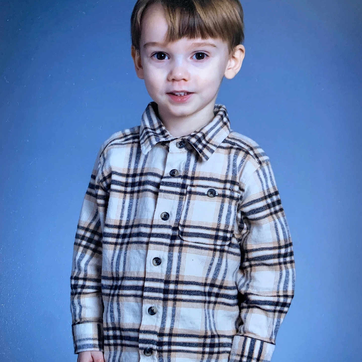 Max is registered to the contest to win money with this photo: child, boy, plaid_shirt, portrait, smile, standing, indoor, blue_background, casual_clothing, young, cute, person, fashion, hair, eyes, face, childhood, happy, model, studio