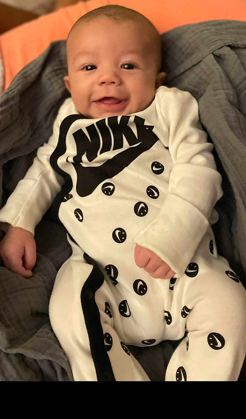 Deaudra joined the competition — help win amazing prizes! baby, infant, smiling, onesie, nike, clothing, blanket, gray, white, black, happy, face, portrait, cute, child, young, indoors, soft, comfortable, lying