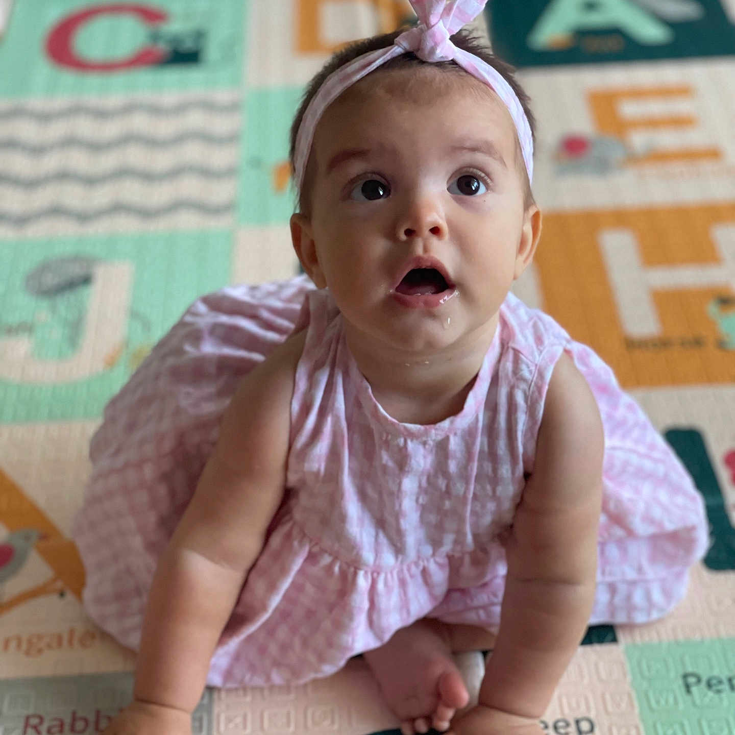 Alba a rejoint le concours — aidez-le/la à gagner de superbes lots ! alphabet, baby, child, clothing, curious, cute, drool, expression, feet, hands, headband, indoor, infant, person, pink_dress, play_mat, portrait, sitting, skin, young