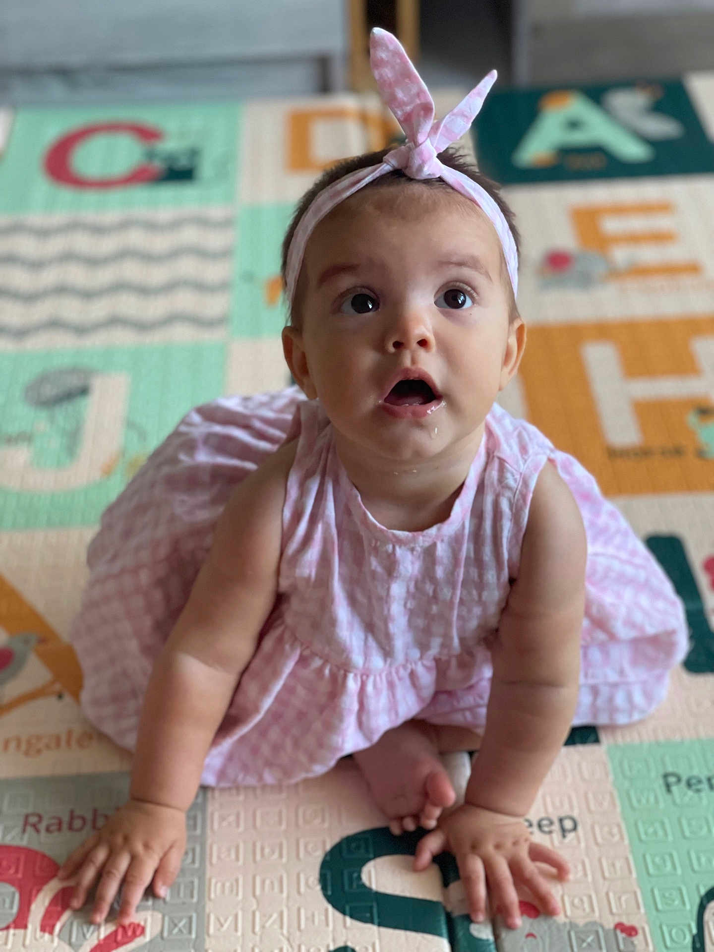 Alba a rejoint le concours — aidez-le/la à gagner de superbes lots ! baby, child, pink_dress, headband, drool, play_mat, alphabet, sitting, curious, cute, indoor, infant, person, skin, hands, feet, expression, young, portrait, clothing