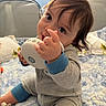 Jack is registered to the contest to win money with this photo: baby, child, infant, toy, speaker, bed, bedding, blue, grey, clothing, face, hand, cute, indoors, playing, sitting, person, young, expression, home