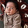 baby, infant, child, portrait, face, eyes, hair, sweater, knitwear, zipper, blanket, football_pattern, brown, cozy, indoor, sitting, close_up, looking_at_camera, adorable, photography