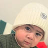 Thiago joined the competition — help win amazing prizes! baby, child, infant, portrait, face, eyes, serious_expression, winter, knit_hat, beanie, sweater, green_clothing, cozy, indoor, close_up, sitting, red_cushion, home, photography, adorable