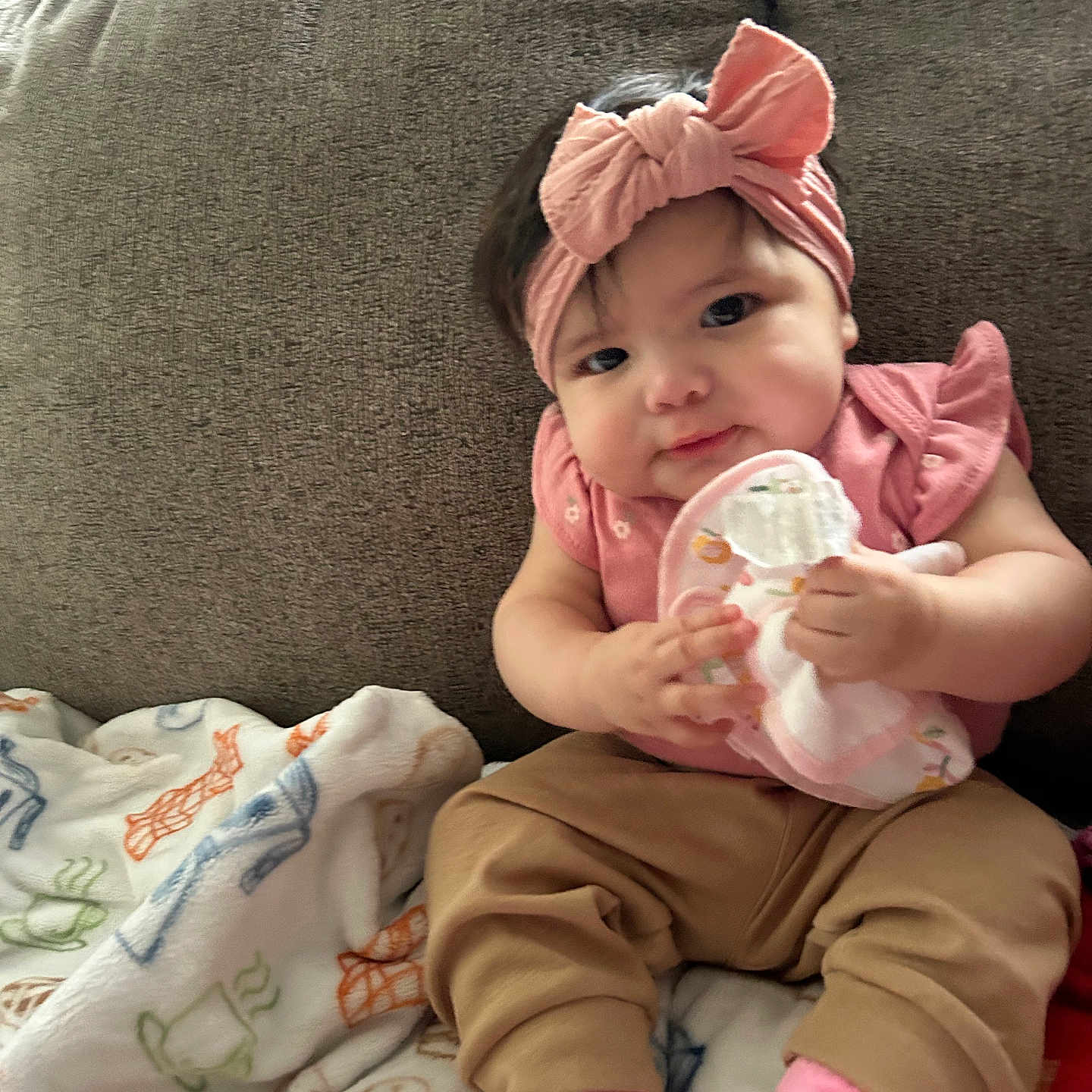 Rylea joined the competition — help win amazing prizes! baby, child, pink_bow, headband, couch, blanket, toy, socks, toddler, infant, clothing, cute, indoor, portrait, person, seated, soft_toy, happy, smile, home