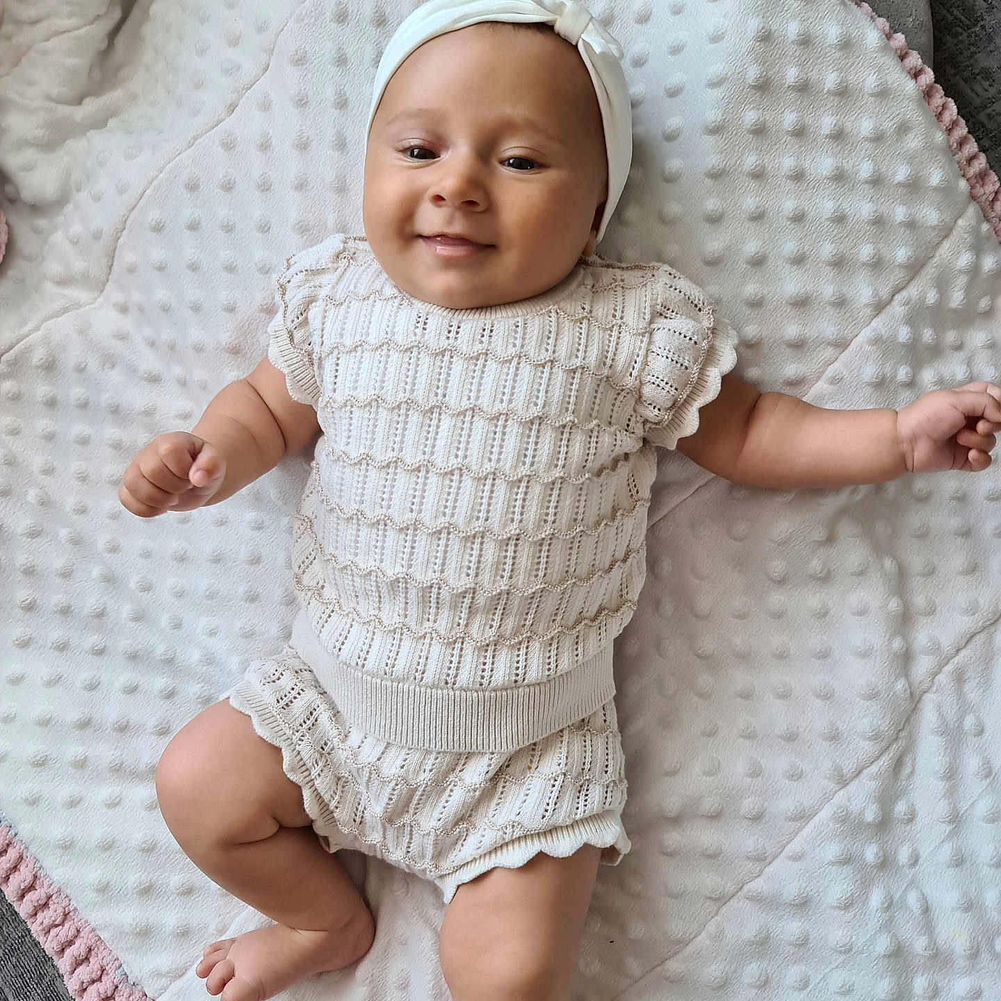 Nuria is registered to the contest to win money with this photo: arm, baby, blanket, child, comfort, cute, happy, headband, indoors, infant, knitwear, leg, lying_down, newborn, person, portrait, skin, smile, soft, texture