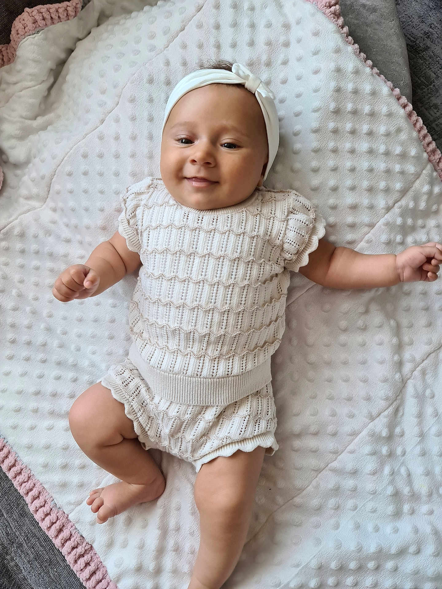 Nuria is registered to the contest to win money with this photo: baby, infant, smile, headband, knitwear, blanket, texture, soft, cute, lying_down, happy, child, skin, arm, leg, indoors, comfort, portrait, person, newborn