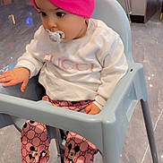 Aaliyah a rejoint le concours — aidez-le/la à gagner de superbes lots ! baby, child, high_chair, pacifier, pink_turban, white_sweatshirt, gucci, mickey_mouse, pink_pants, pink_shoes, socks, indoor, floor, chair, person, cute, fashion, seated, curious, infant