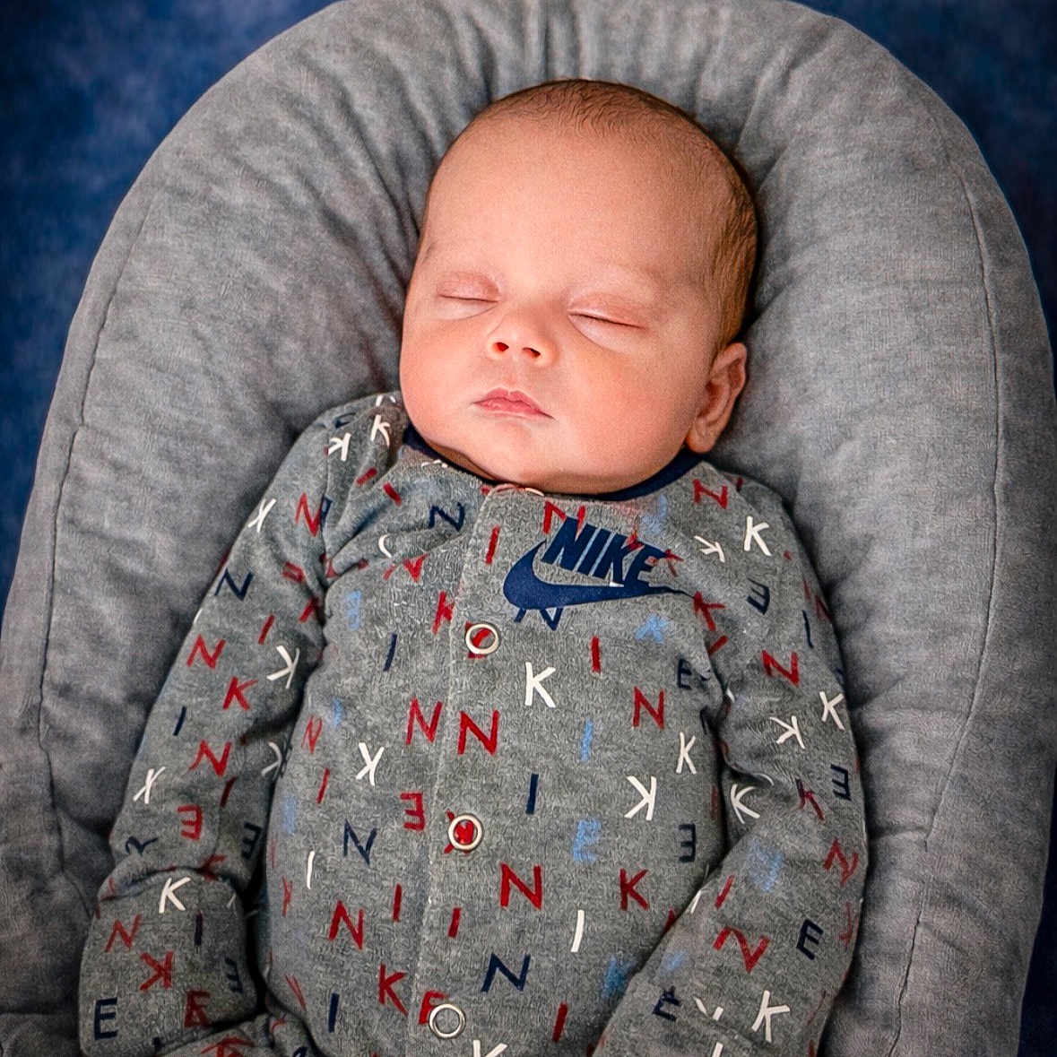 Camden is registered to the contest to win money with this photo: baby, child, clothing, comfortable, cozy, cushion, cute, face, gray, indoor, infant, newborn, nike, onesie, peaceful, portrait, relaxing, rest, sleeping, soft