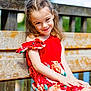 child, girl, smile, red_dress, flowers, bench, wood, outdoor, sunlight, happy, portrait, nature, grass, summer, casual_clothing, sitting, young, cute, daylight, background_blur