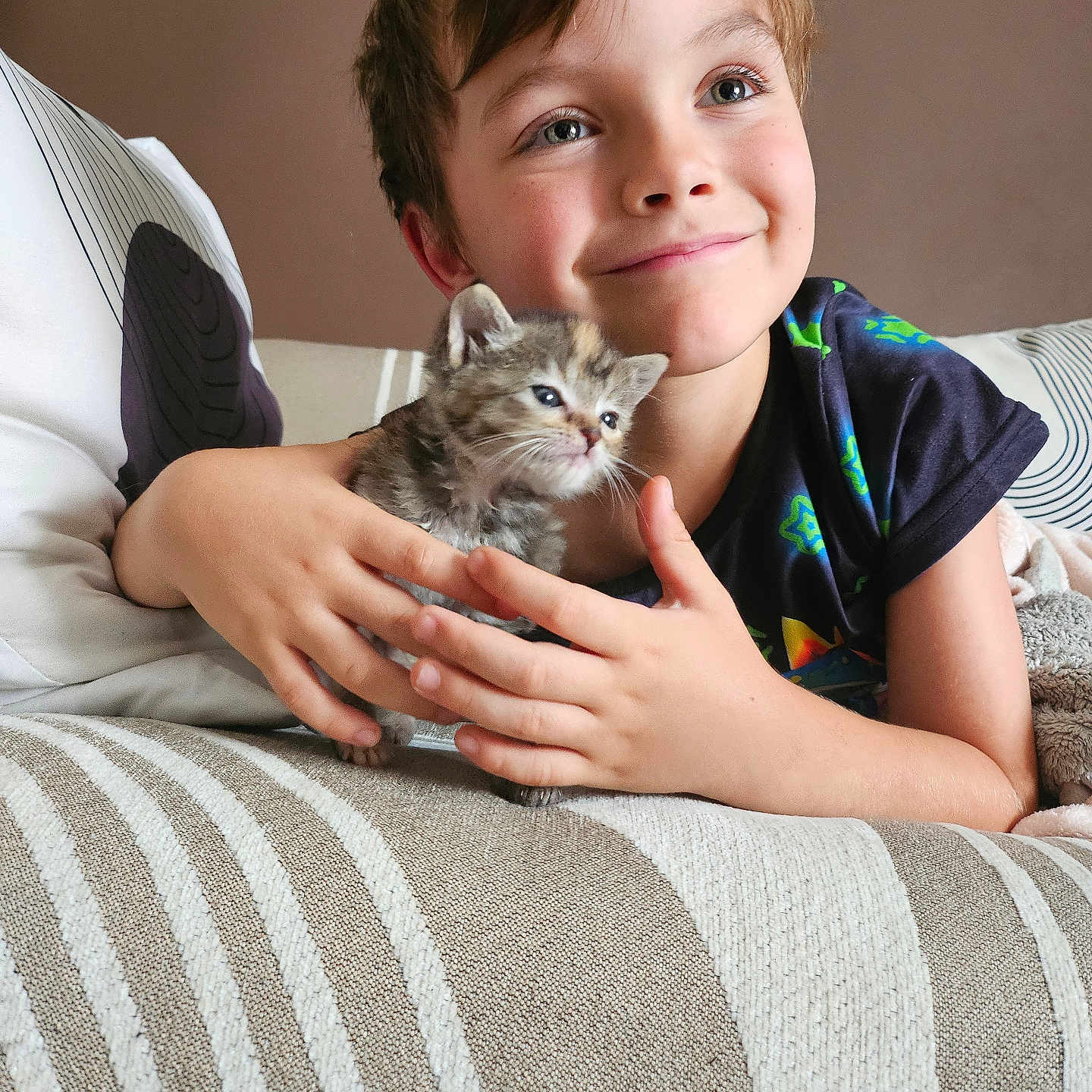 Cheshire participe au concours pour gagner de l'argent avec cette photo : animal, casual_clothing, cat, child, couch, cozy, curly_hair, cute, furniture, hands, happy, home, indoor, kitten, pet, portrait, resting, smiling, striped_blanket, young_boy