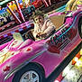 amusement_park, barbie, bumper_car, cartoon, child, colorful, entertainment, face, fun, indoor_ride, lights, pink_coat, playful, portrait, ride, smiling, toy_car, vehicle, winter_clothing, young_child