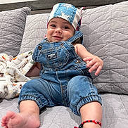 Emiliano joined the competition — help win amazing prizes! baby, denim_overalls, headscarf, smiling, couch, blanket, bracelet, foot, hand, quilted, indoor, child, cute, apparel, portrait, infant, comfortable, happy, clothing, relaxed