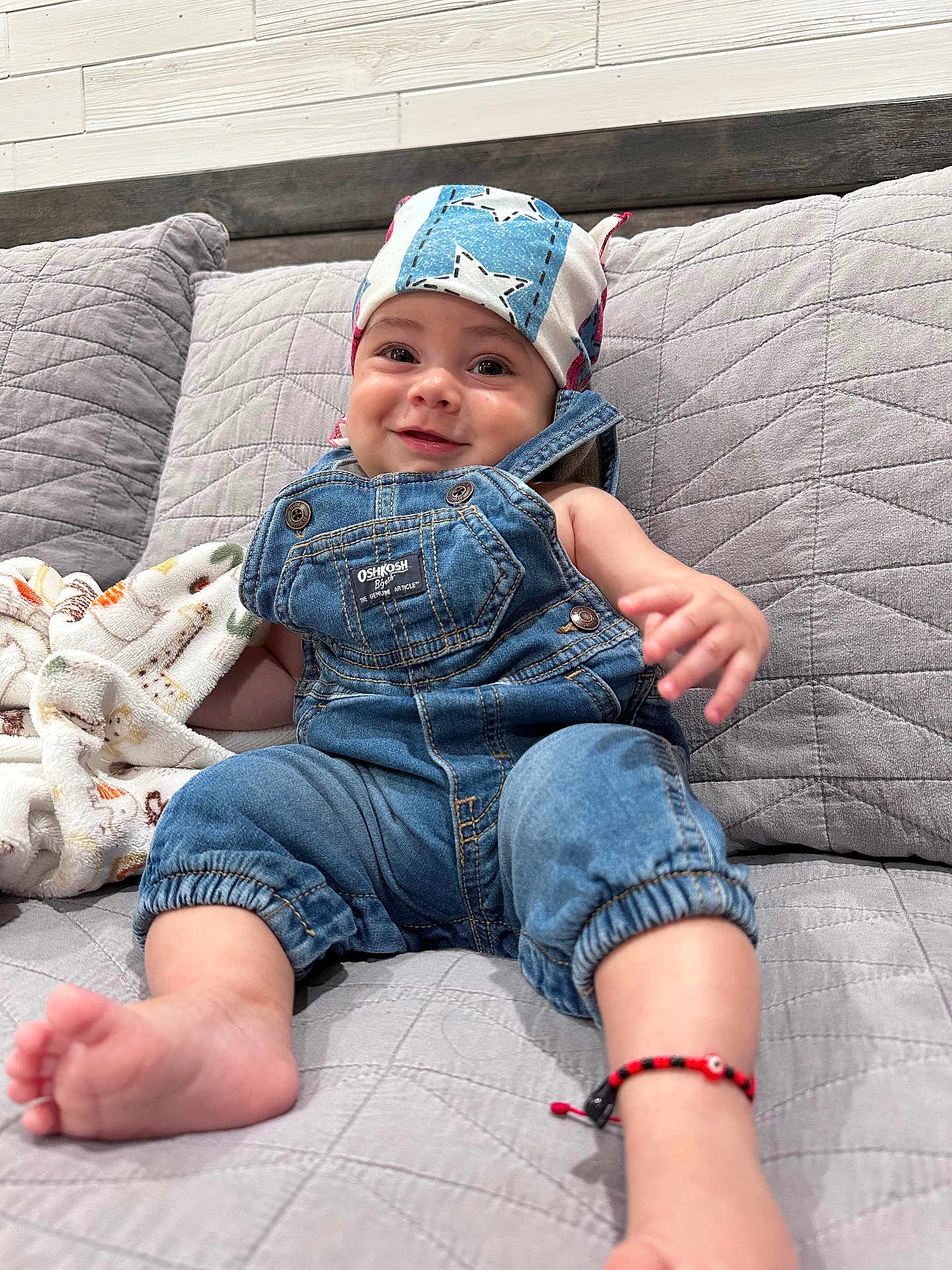 Emiliano joined the competition — help win amazing prizes! baby, denim_overalls, headscarf, smiling, couch, blanket, bracelet, foot, hand, quilted, indoor, child, cute, apparel, portrait, infant, comfortable, happy, clothing, relaxed